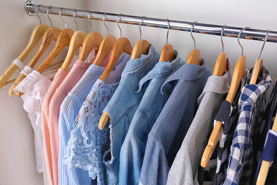 Closeup of Hangers with Different Clothes in Wardrobe